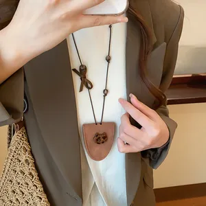 Close-up of stylish brown triangular glasses holder necklace with leopard bear charm detail.