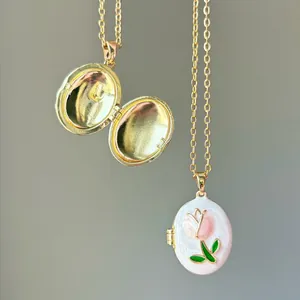 Close-up of open and closed pink tulip enamel locket necklaces in gold finish.