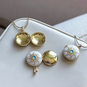 Close-up of a gold locket necklace with white sunburst enamel and blue zircon center.