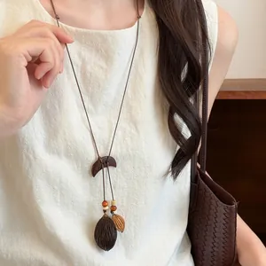 Close-up detail of bohemian wooden crescent pendant featuring natural seed and nut charms