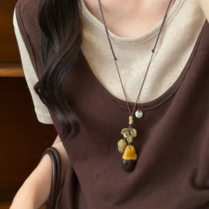 Close-up of vintage wooden acorn pendant necklace with rustic leaf details on brown cord