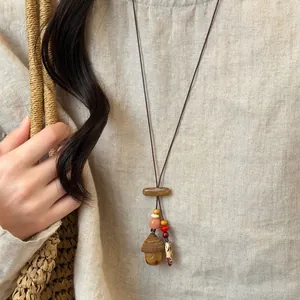 Detailed view of bohemian wooden pendant necklace with colorful beads on linen