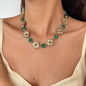 Detailed view of vintage gold flower necklace with emerald green resin beads on model's neck