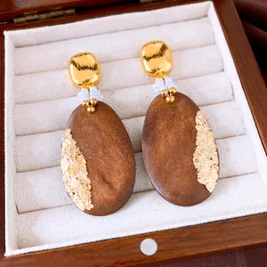 Macro view of vintage oval wooden drop earrings decorated with gold foil and white pearls