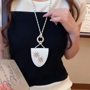 Close-up of a sunflower eyeglass clip necklace on a model wearing a black top