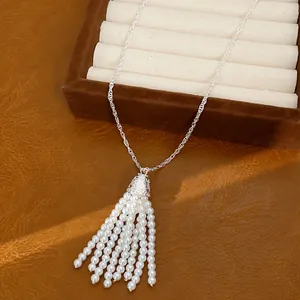 Elegante weiße Perlenquasten-Halskette mit Silberkette auf braunem Lederhintergrund