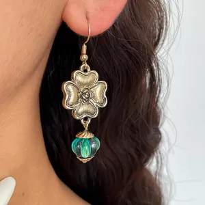 Vintage gold metal flower dangle earrings with a green translucent lantern resin bead detail