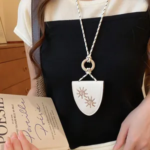 Detail view of a white leather sunflower eyeglass holder necklace on a model.