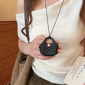 Detailed view of the black woven mini bag pendant on a long multi-functional necklace
