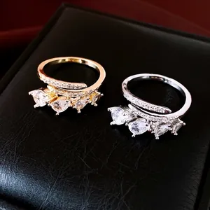 Elegante gouden en zilveren open ringen met druppelvormige zirkonia op een juwelendoos