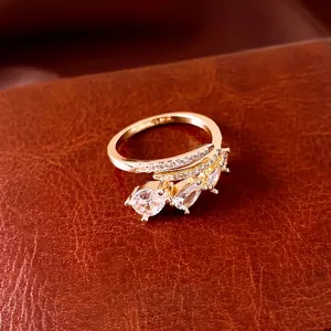 Elegante gouden open ring met waterdruppel zirkonia op een bruine lederen achtergrond