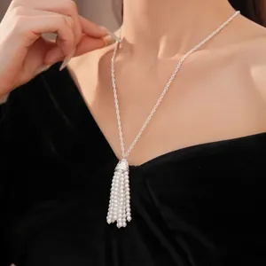 Elegantes Detail einer weißen Perlenquasten-Halskette an einem Model in Schwarz