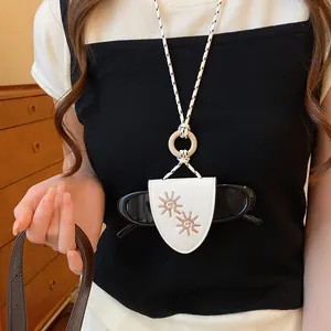 Close-up of white sunglasses holder necklace with embroidered sun pattern and wooden ring.
