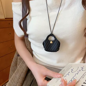 Unique black woven mini bag pendant necklace shown on minimalist white top as lifestyle detail