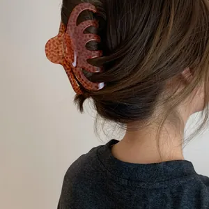 Detailed view of a large leopard print acrylic hair claw clip used in a bun hairstyle.