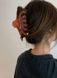 Detailed view of a stylish leopard print acrylic hair claw clip used on a woman's bun.