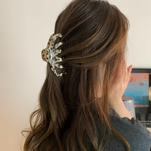 Detailed view of a large leopard print acrylic hair claw clip worn on wavy brown hair