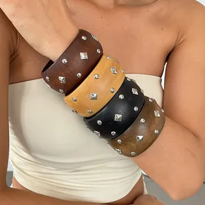 Close-up of four stacked ethnic wooden bangles with square and round metal studs