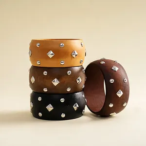 Detailed view of handmade wooden bangles featuring geometric pyramid and round metal studs