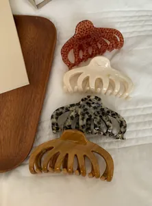 Macro view of four stylish acrylic hair claw clips in leopard, marble, and amber tones