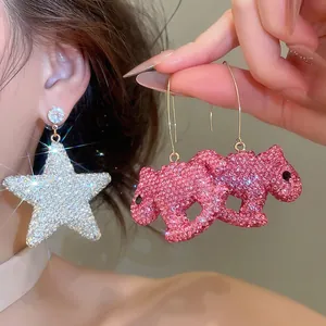 Vue détaillée de boucles d'oreilles scintillantes en cristal, avec étoile et animal rose