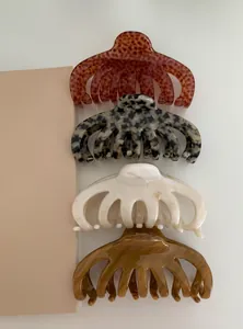 Detailed view of four acrylic hair claws in assorted marbled and leopard patterns