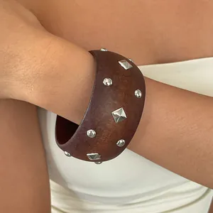 Close-up of ethnic style wooden bangle with silver pyramid and round studs on a model wrist