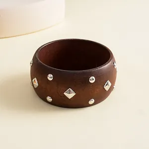 Detail view of a retro wooden bangle with geometric silver-toned rivets
