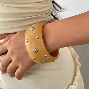 Detailed view of a retro wooden bangle featuring geometric silver studs worn on a wrist