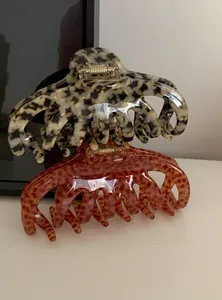 Detailed macro view of two large acrylic leopard print hair claw clips with glossy finish