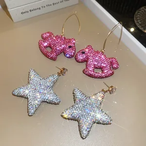 Gros plan de boucles d'oreilles pendantes en forme de cheval et d'étoile en strass.