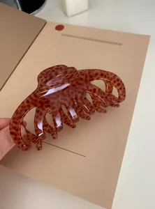 Detail of a large acrylic hair claw clip with a glossy brown leopard print pattern