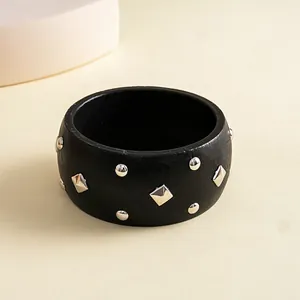 Detail view of ethnic black wooden bangle decorated with silver diamond metal studs.