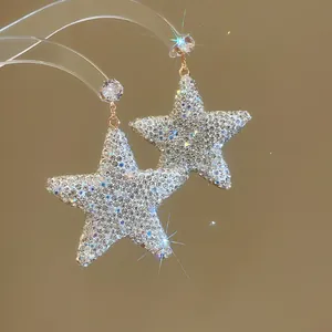 Gros plan de boucles d'oreilles pendantes en étoile entièrement ornées de strass