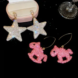 Détail de boucles d'oreilles pendantes en argile avec étoile et cheval à bascule