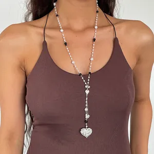 Close-up of retro heart pearl necklace with large silver filigree pendant on model