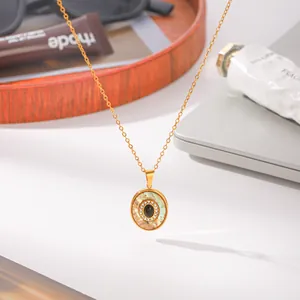 Gedetailleerde weergave van gouden ronde hanger met zwarte obsidiaan en abalone schelp inleg