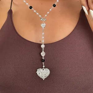 Detailed view of a vintage Y-shaped pearl necklace with textured silver heart pendants