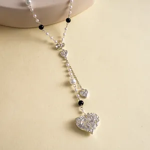 Close-up detail of a vintage silver-toned heart pendant with pearls and bow decoration