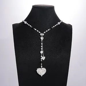 Detailed view of a retro pearl necklace with heart charms and a decorative bow charm