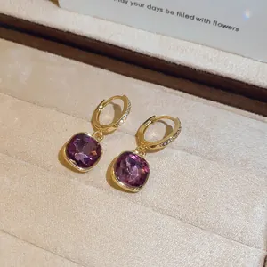 Detailopname van vintage gouden oorbellen met elegante gefacetteerde paarse kristallen