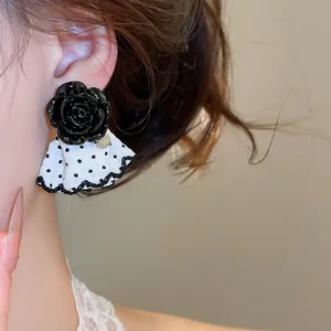 Close-up of black flower stud earrings with polka dot skirt detail on model's ear