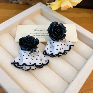 Detailed view of elegant black rose stud earrings with white polka dot fabric skirt design