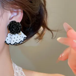 Close-up of black rose stud earring with black and white polka-dot ruffle detail