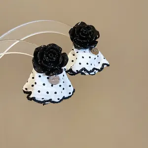 Exquisite detail of black rose earrings featuring a white polka dot fabric skirt design