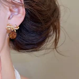 Detailopname van elegante vintage zirkoon strik oorbellen met bruine geometrische hanger