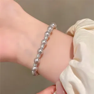 Elegantes graues Perlenarmband mit funkelnden Silberperlen, nah am Handgelenk einer Frau.