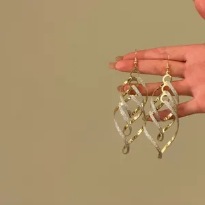 Gedetailleerde close-up van elegante goud-zilveren gedraaide spiraalvormige hangeroorbellen