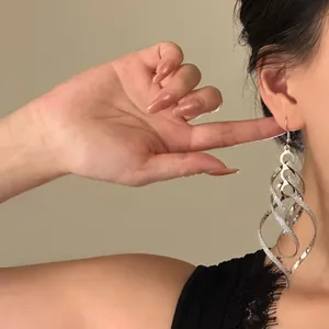 Elegante close-up van een vrouw die gedraaide zilveren ruitvormige hangende oorbellen draagt