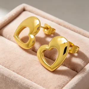 Macro view of polished 3D hollow heart gold titanium steel stud earrings in jewelry box